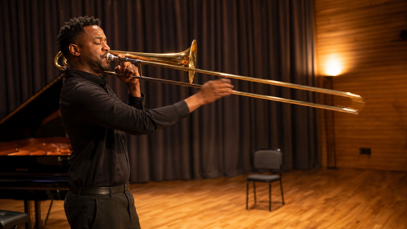 Trombonist practicing a glissando in a warm rehearsal space