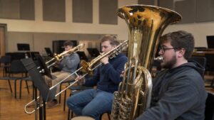 Tuba player warming up with low brass section in a rehearsal room